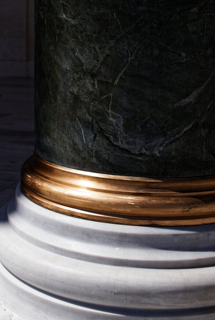 High-quality close-up of a marble column with gold detailing, showcasing texture and elegance.